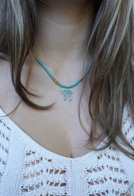 The Hërzliya Necklace: turquoise seed beads with gold-tone accents and a blue-green stone chai pendant