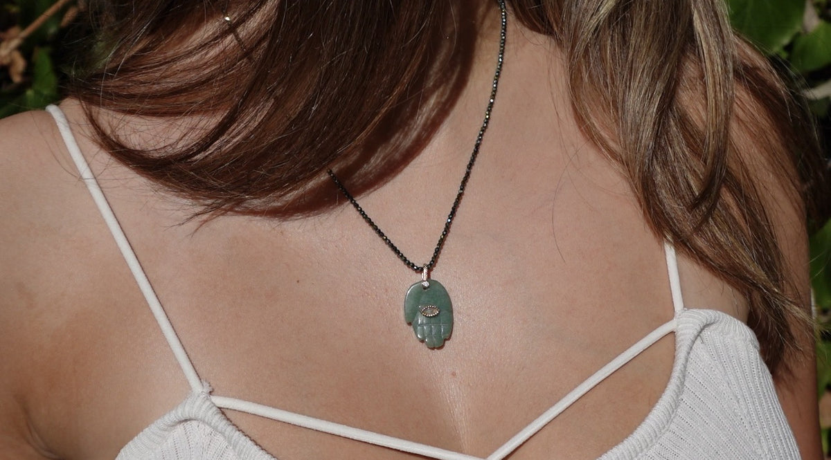 The Jërusalem Necklace: a green stone hamsa pendant on fine faceted dark beads