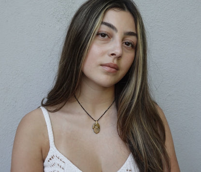 The Nëtanya Necklace: a carved golden-brown stone hamsa on fine faceted black beads